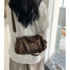 A woman is holding a brown leopard print Rivet Boston shoulder bag against a white shirt.