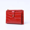 A red leather card holder with a crocodile pattern and a zipper closure.