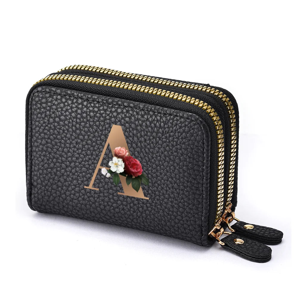 Black faux leather mini wallet with a gold letter A and floral design and a double zipper.
