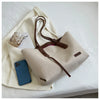 A beige canvas shoulder tote bag with brown leather straps and a smartphone resting on the fabric.