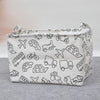 A white foldable fabric storage basket with handles featuring line drawings of various vehicles and objects.