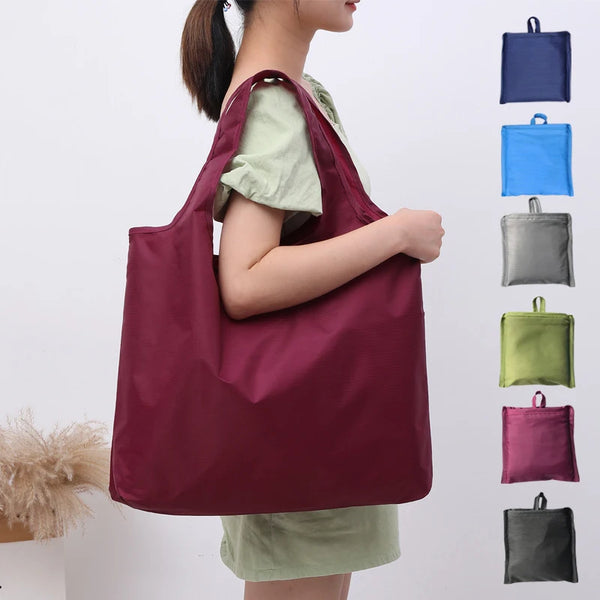 A person is holding a deep maroon reusable eco-friendly folding shopping bag with various colored fabric options.