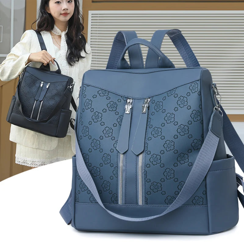 A navy blue leather anti-theft women's backpack with a floral pattern is shown next to a woman.