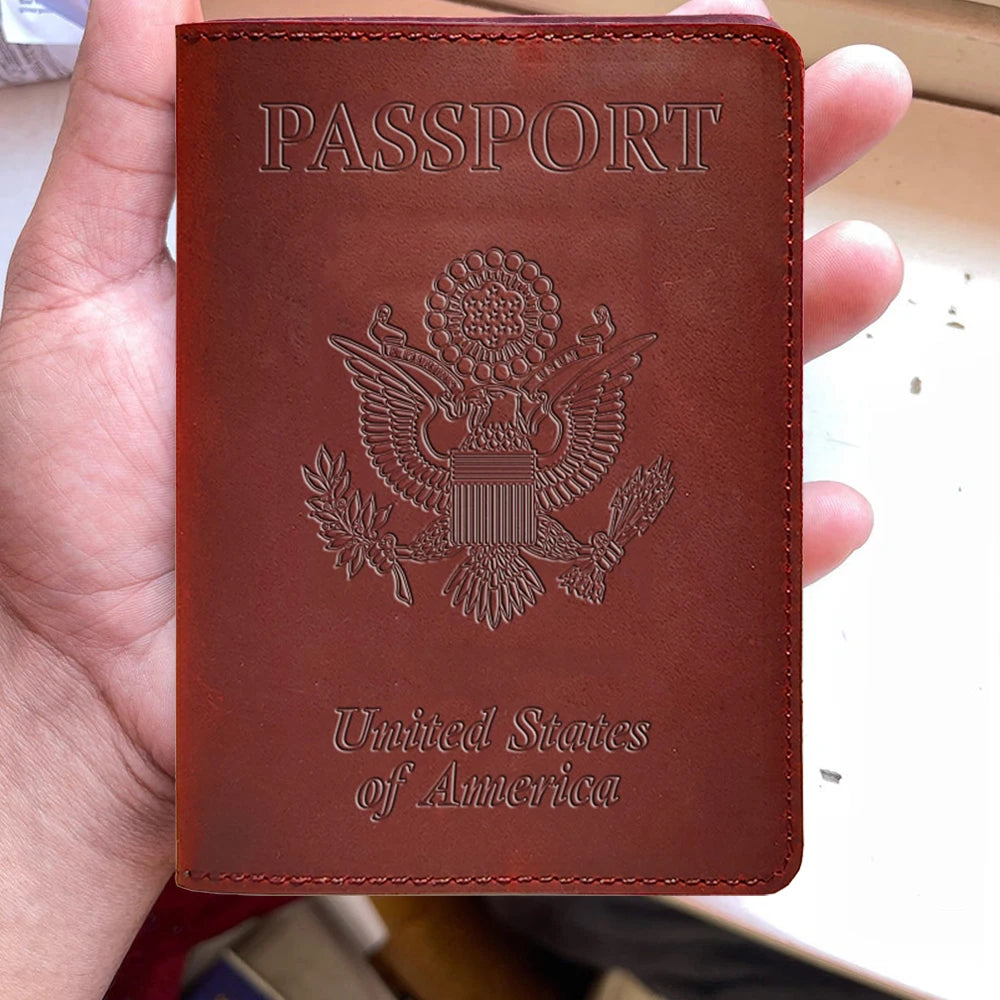A brown leather passport holder with embossed text and an eagle emblem is held in a hand.