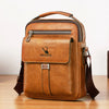 A brown vintage PU leather crossbody messenger bag with a zipper and leather strap resting on a wooden surface.