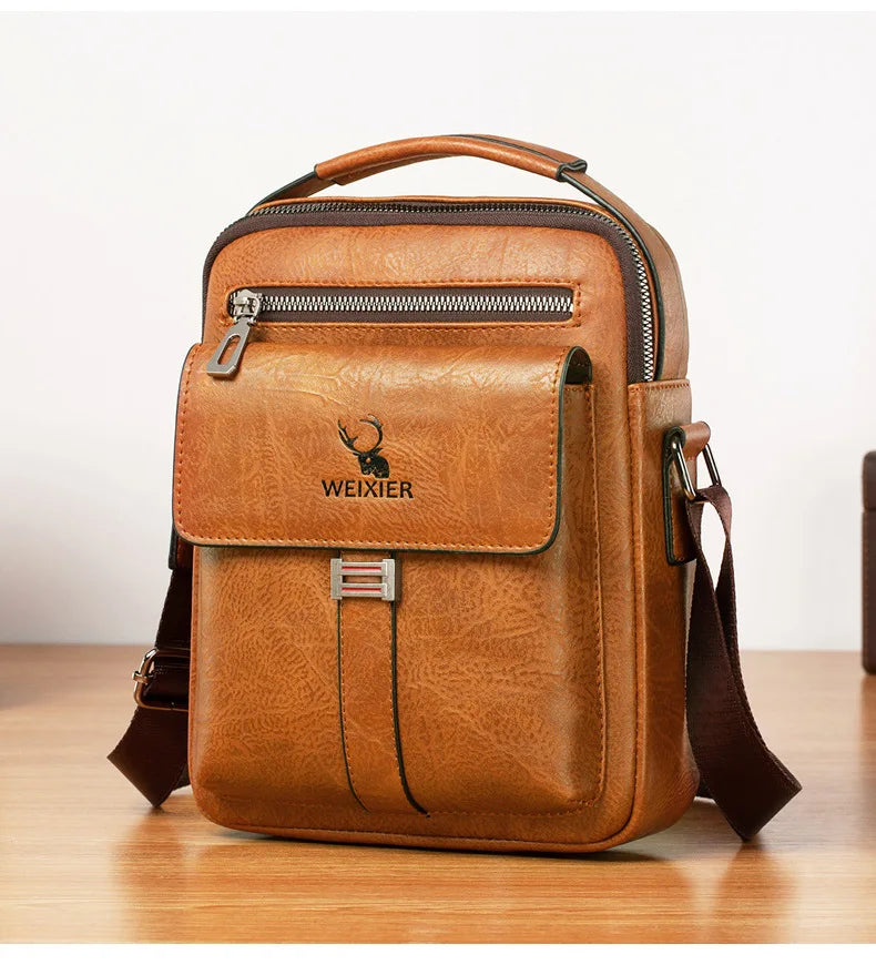 A brown vintage PU leather crossbody messenger bag with a zipper and leather strap resting on a wooden surface.