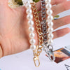 A hand holds a gold and silver pearl chain shoulder strap for bags.