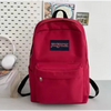 Un sac à dos Jansport rouge vu de l'arrière, posé sur une surface blanche.
