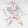 A pink and white floral patterned diagonal shoulder strap for bags displayed on a white box.