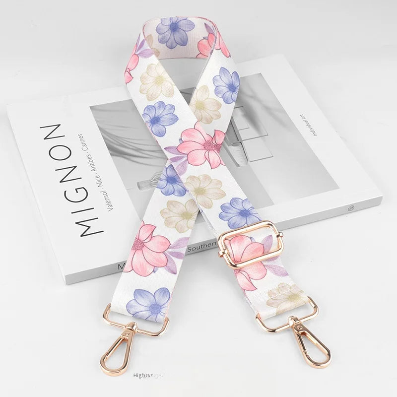 A pink and white floral patterned diagonal shoulder strap for bags displayed on a white box.