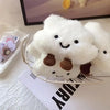 A white fluffy cloud shaped plush toy with brown spots is displayed on a silver wire tray.