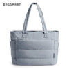Sac fourre-tout rembourré et matelassé gris avec poignées rembourrées, présenté sur fond blanc.