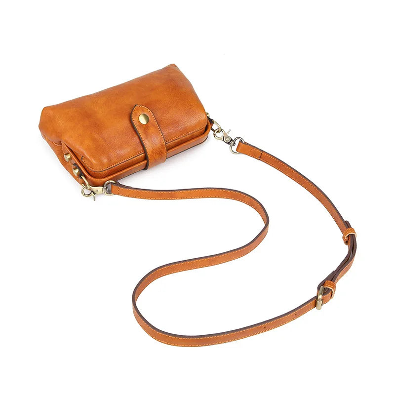 A tan genuine leather crossbody bag with a buckle closure.