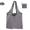A black and white striped reusable eco tote shopping bag hanging against a white background.