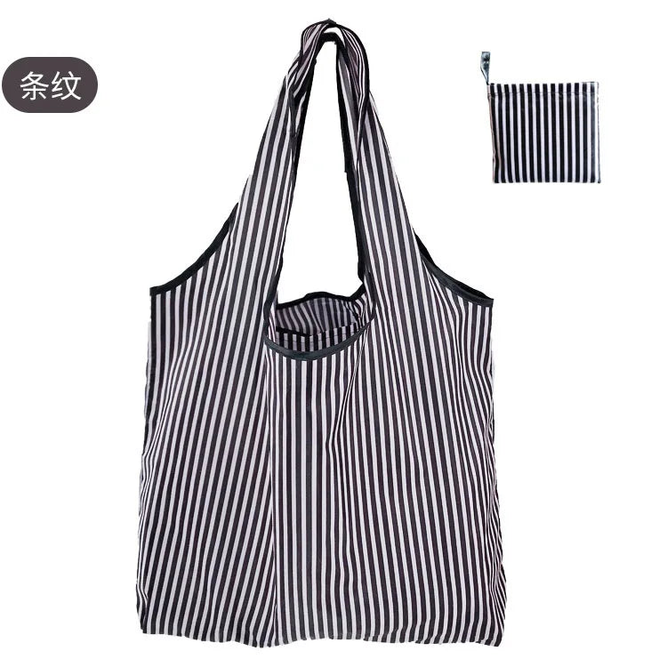 A black and white striped reusable eco tote shopping bag hanging against a white background.