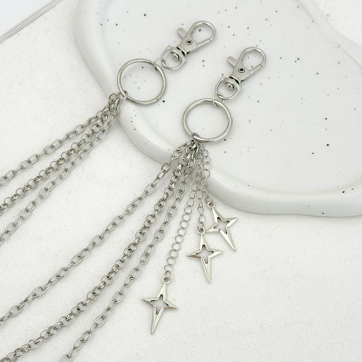 Silver punk star chain belt with pearl accents displayed on a white surface.