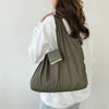 A person is holding a olive green reusable nylon mini keychain tote bag with a gold accent.