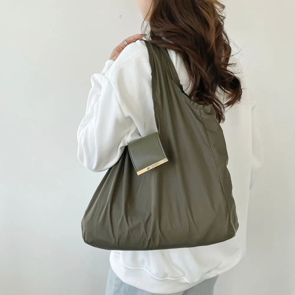 A person is holding a olive green reusable nylon mini keychain tote bag with a gold accent.