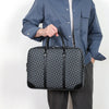A person holds a dark gray luxury PU leather business briefcase against a white background.