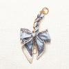 A light blue and gray patterned fabric bow with a gold chain strap extension for a handbag.