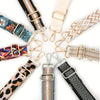 A collection of various patterned and colored adjustable nylon crossbody bag straps.