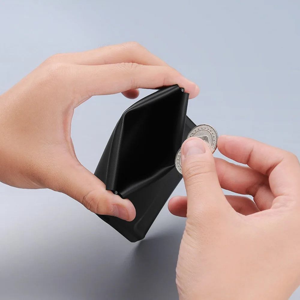 A hand is opening a black magnetic foldable ID card holder to reveal a coin purse inside.