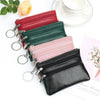 A collection of stacked PU leather clutch wallets in red, green, pink, and black, with a white cup nearby.