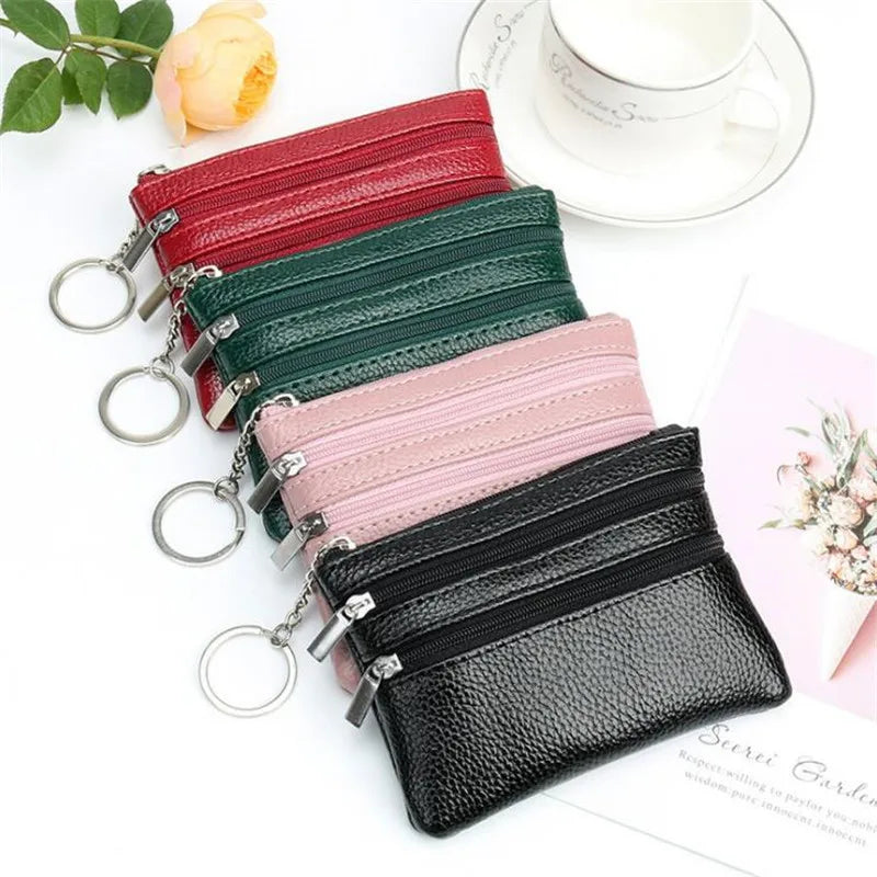 A collection of stacked PU leather clutch wallets in red, green, pink, and black, with a white cup nearby.