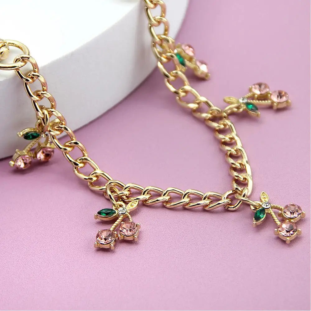 Gold chain necklace with pink and green floral pendants displayed on a light background.
