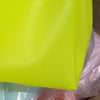 Un sac en filet transparent jaune néon brillant, montré dans un sac plastique.