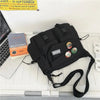 A black nylon crossbody shoulder bag is displayed on a white desk next to a laptop and a book.