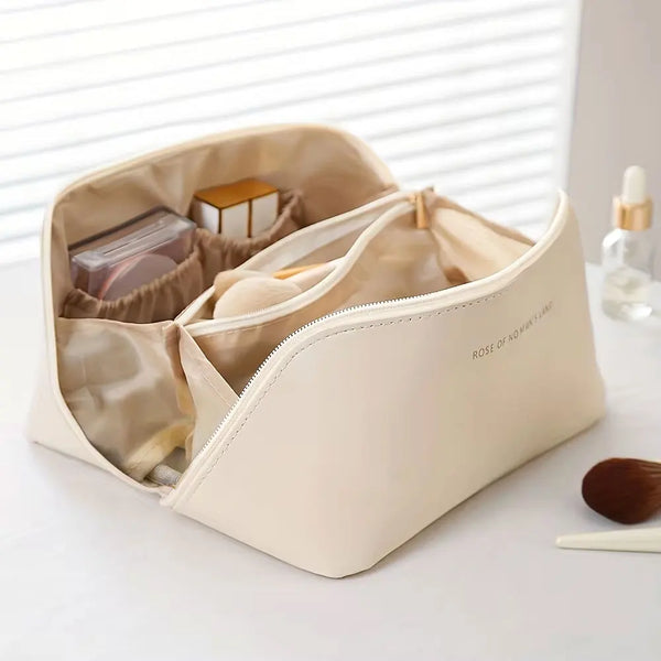Pochette organisatrice de maquillage beige luxe avec fermeture éclair et extérieur lisse sur une surface blanche.