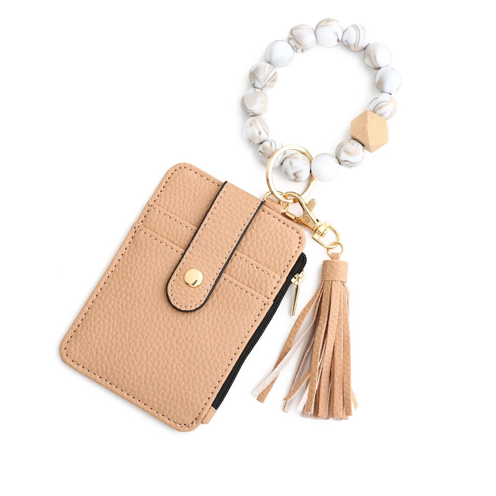 Tan leather card holder with a gold keychain and a white beaded bangle