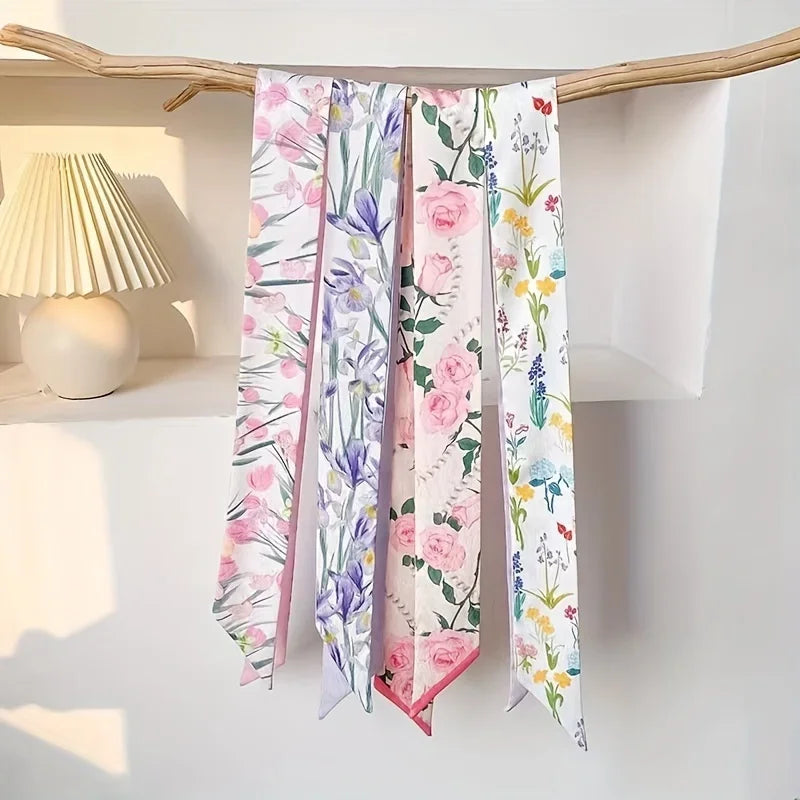 Écharpes de cheveux en soie élégantes avec des motifs floraux dans des tons roses, violets et verts, suspendues à un support 