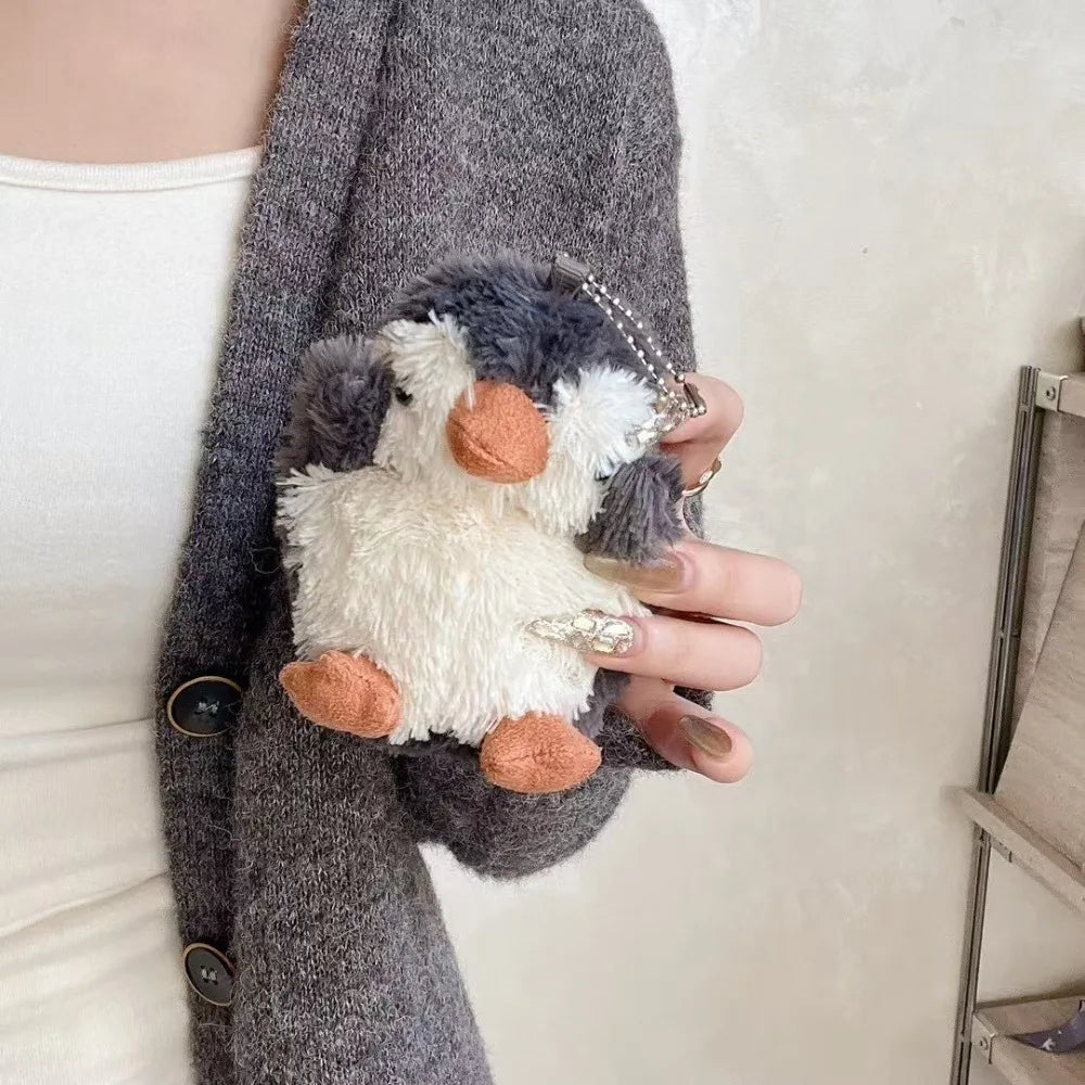 A fluffy white elephant plush toy is held in a hand against a gray knitted sleeve.