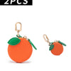 Two orange cherry fruit shape coin purse keychains with green fabric and gold-tone hardware.