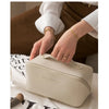 A beige foldable cosmetic storage bag being held by a person in a soft, natural light setting.