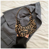 A leopard print PU leather mini tote handbag resting on a gray blazer against a light background.