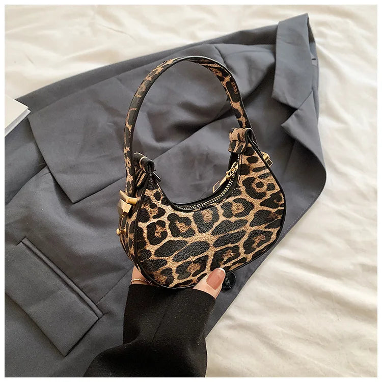 A leopard print PU leather mini tote handbag resting on a gray blazer against a light background.
