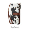 A brown leather trifold clutch wallet featuring a black and white cow pattern.