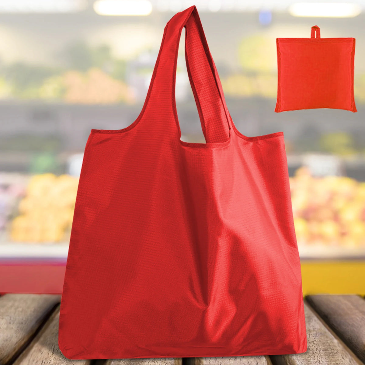 A bright red reusable foldable grocery tote bag is shown in a close-up view.