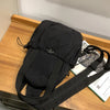 A black versatile casual backpack with a strap is shown resting on a wooden surface.