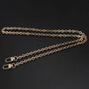 A gold-colored metal chain strap for an adjustable crossbody bag, laid out on a dark surface.