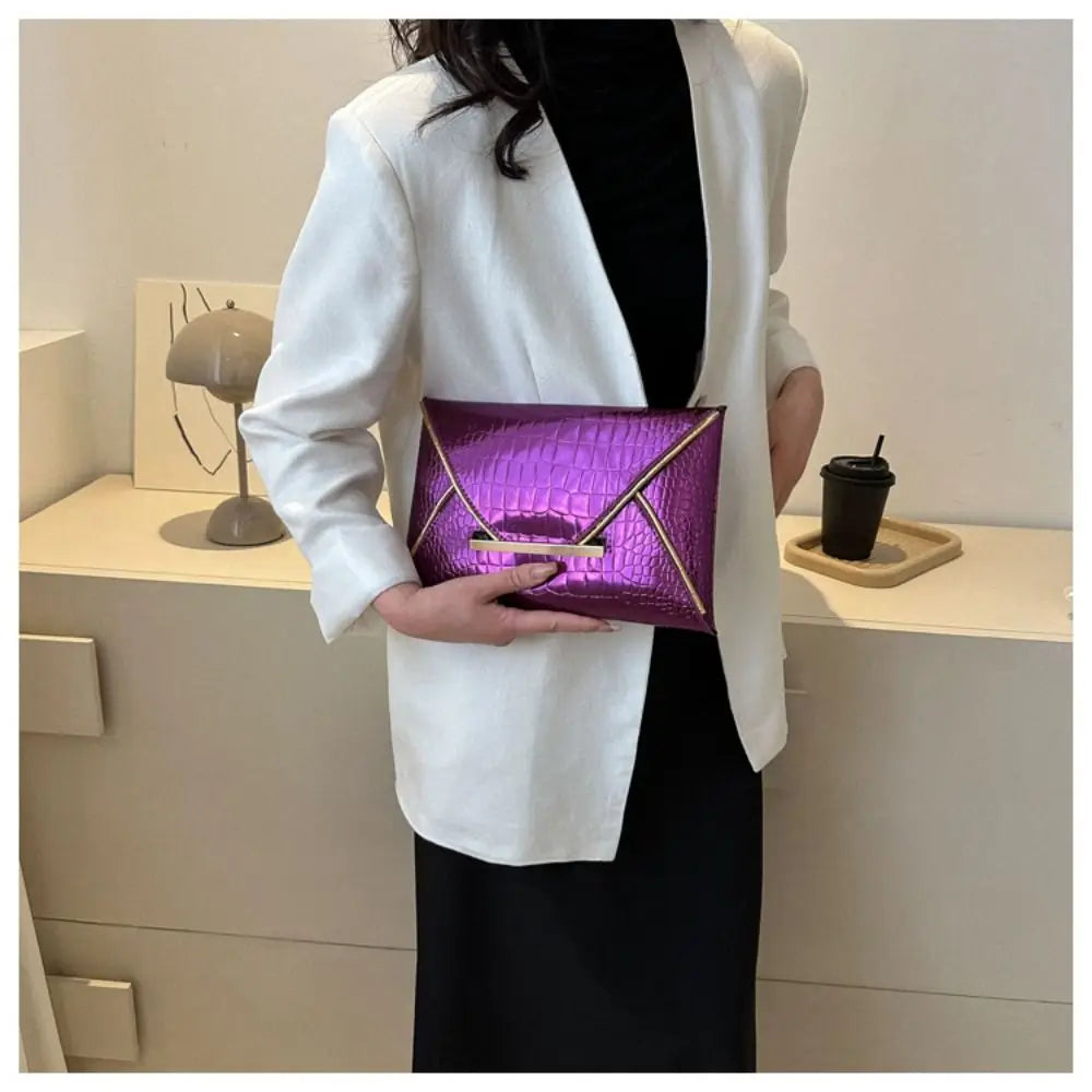A woman holds a purple crocodile pattern coin purse clutch in front of a white blazer against a light background.