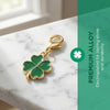 Gold-toned four leaf clover charm on a silver chain displayed on a white marble surface.