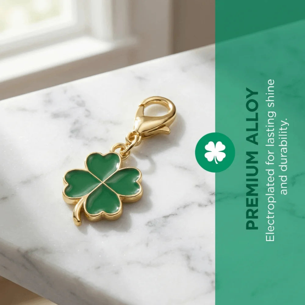 Gold-toned four leaf clover charm on a silver chain displayed on a white marble surface.