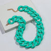 A bright turquoise matte acrylic chain necklace with gold accents displayed on a white box.