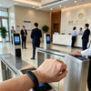 Une main interagit avec un dispositif électronique argenté, probablement un lecteur de bracelet de protection RFID.