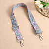 A pink and blue bohemian printed fabric strap with silver hardware is displayed on a beige background.