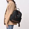 A woman wearing a beige blazer holds a black nylon travel backpack.